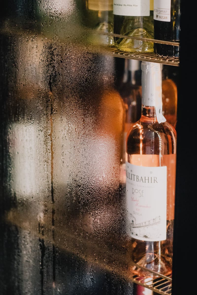 Chilled wine bottles behind a misted fridge door