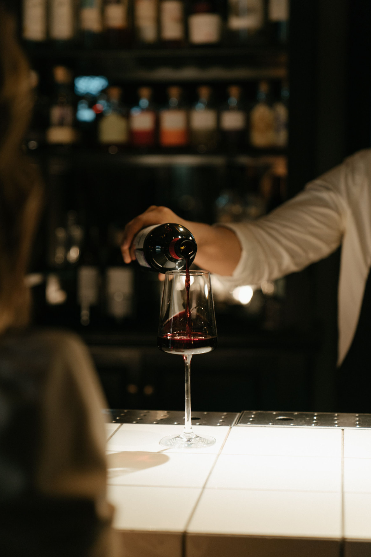 A restaurant server pouring red wine